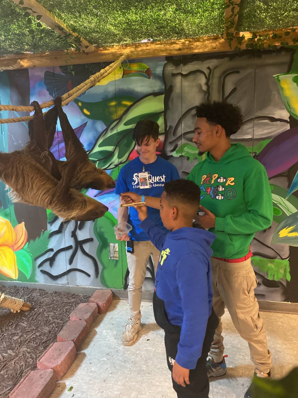 Kids feed a sloth at SeaQuest