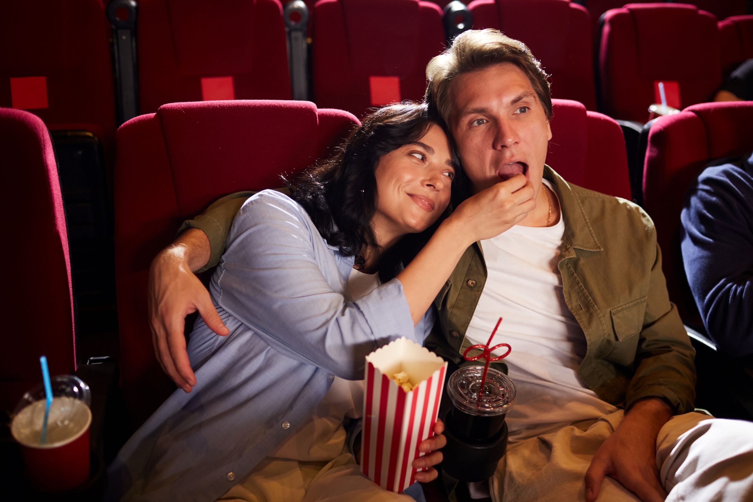 Couple eat popcorn together at movie theater